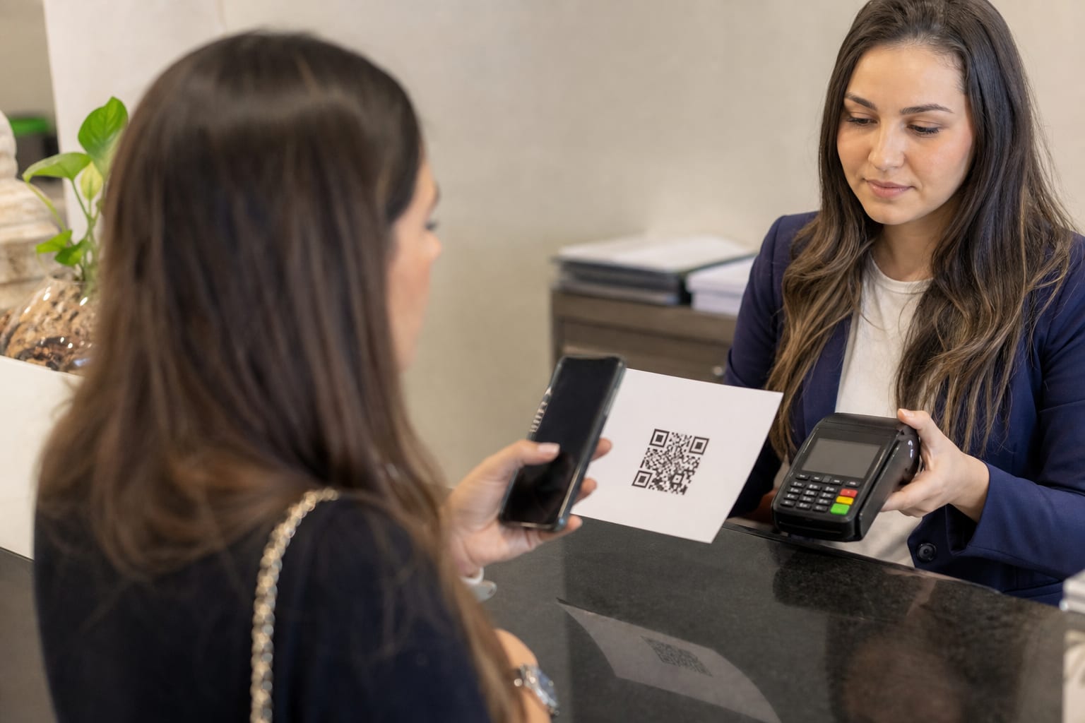 Recepção de escritório contábil com maquininha de cartão, celular e papel com código para pagamento